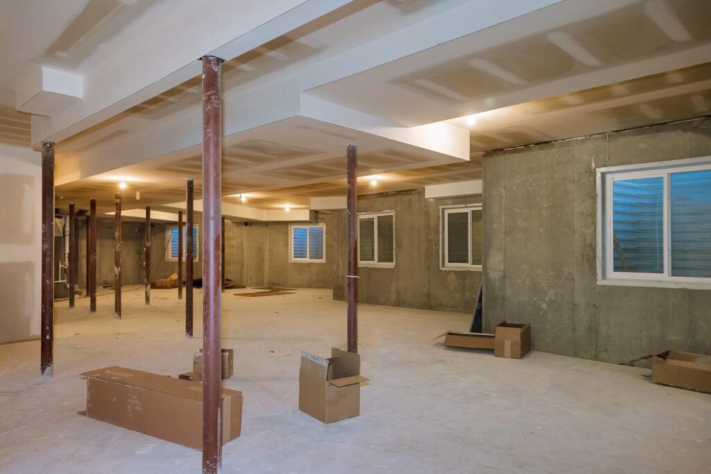 Basement under construction with exposed wiring, plumbing, and unfinished concrete flooring.