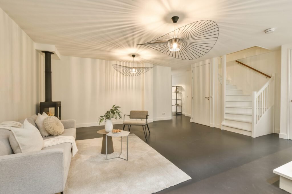 Finished basement with grey floors, white walls, white ceiling, white couch, and a wood stove in the corner.